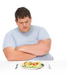 Image showing Unhappy, angry and man frustrated by healthy food, meal or salad diet isolated in a studio white background. Obesity, overweight and young man with eating problem and sad for a plate with lettuce