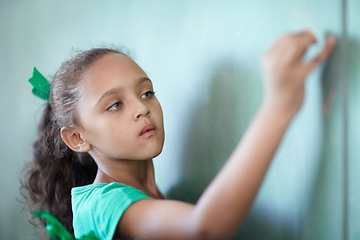 Image showing Education, focus and a girl writing on a chalkboard for learning, studying and teaching in class. Creative, concentration and a young student at a blackboard for a presentation or classroom notes