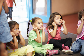 Image showing School children on floor listening to teacher for anatomy education, hearing exercise and learning in classroom. Class, group and kids on ground with attention, discipline and kindergarten or creche