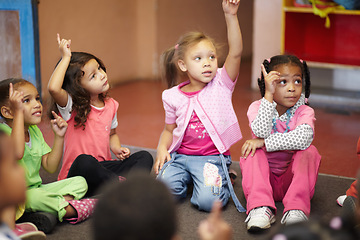 Image showing Education, kindergarten and kids asking a question with hands raised while sitting on a classroom floor for child development. School, learning or curiosity with children in class to study for growth