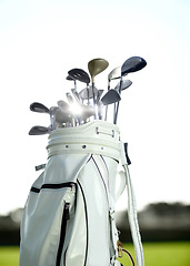 Image showing Golf bag, sports and clubs outdoor on course for training, workout or summer sport on green field sunset mockup. Golfer, bags and equipment for game, competition or exercise with blue sky lens flare.