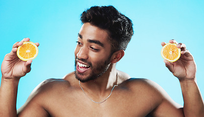 Image showing Skincare, orange and face of man in studio for beauty, wellness and citrus treatment on blue background. Fruit, facial and portrait of indian male model excited for organic vitamin c skin cosmetics