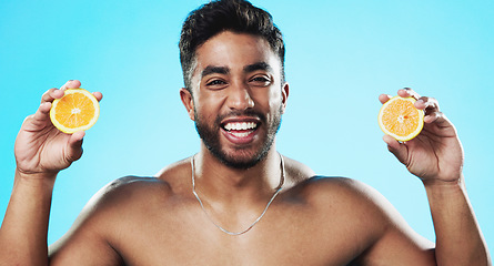 Image showing Skincare, orange and face of man in studio for beauty, wellness and citrus treatment on blue background. Fruit, facial and portrait of indian male model excited for organic vitamin c skin cosmetics