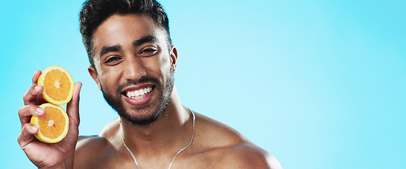 Image showing Beauty, orange and face of man in studio for skincare, wellness and citrus treatment on blue background. Fruit, facial and portrait of indian male model excited for organic vitamin c skin cosmetics