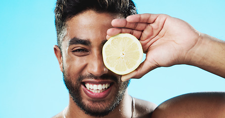 Image showing Skincare, lemon and face of man in studio for beauty, wellness and citrus treatment on blue background. Fruit, facial and portrait of indian guy model relax with organic, anti aging or skin cosmetics