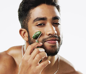 Image showing Face, beauty and man with facial roller, skincare and cosmetics against a grey studio background. Portrait, male ad guy with rose quartz, treatment and grooming with confidence, smooth and soft skin