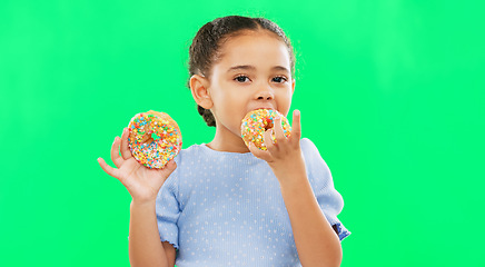 Image showing Candy, smile and child eating donuts on green background with cake for party, birthday and luxury. Food, excited kid and isolated happy girl with sweets, dessert treats and sugar doughnuts in studio