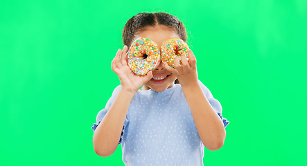 Image showing Donut on eyes, smile and child on green background with cake over face for funny, meme and comic. Food, excited kid and isolated happy girl with sweets, dessert treats and sugar doughnuts in studio