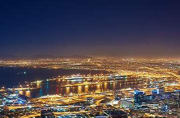 Image showing Night, city and lights with landscape, buildings and urban development with traffic, transport and streets. Evening, dark and road with network, Cape Town and highway with water, growth and travel