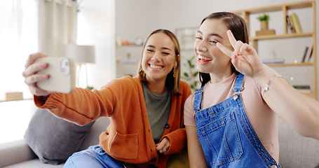 Image showing Phone, selfie and friends on a living room sofa taking a profile picture together for social media. Digital, women and girl friend in a home with peace sign posing on a mobile for web app in house
