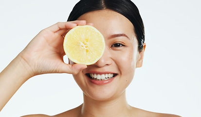 Image showing Lemon, face and woman in studio, natural wellness and white background. Happy asian model, beauty portrait and citrus fruits for facial cosmetics glow, vitamin c skincare or detox dermatology results