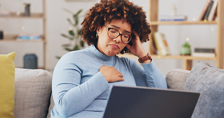 Image showing Laptop, bad news and loss with a woman on a sofa in the living room of her home feeling unhappy or emotional. Computer, shock and grief with a sad young female reading an email or social media feed