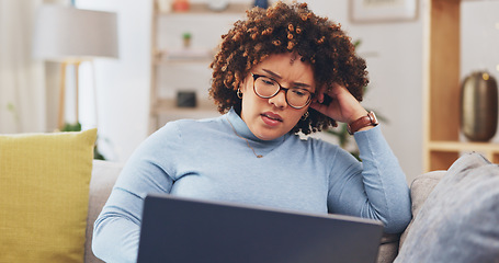 Image showing Laptop, bad news and grief with a woman on a sofa in the living room of her home feeling sad or emotional. Computer, shock and loss with an unhappy young female reading an email or social media feed