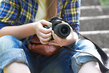 Image showing Woman, photographer hands and camera for travel picture sitting on garden steps. Journey, photo and photography of a female person in a urban park traveling and outdoor on holiday with hobby