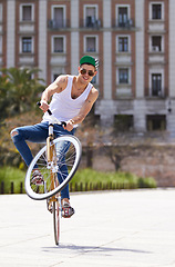 Image showing Fitness, city and man riding a bicycle and practicing tricks and skills for a competition. Activity, hobby and casual young male person training and cycling outdoor with a bike in an urban town road.