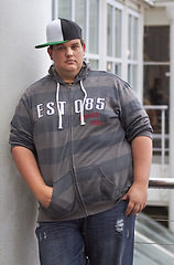 Image showing Plus size, young guy and portrait outdoor with hipster and urban style feeling serious. Student, gen z fashion and cool clothing of a heavy male person with youth and confidence with hands in pocket