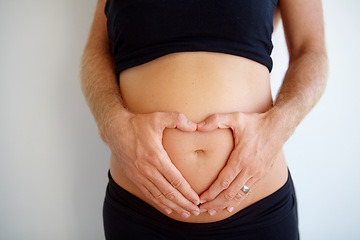 Image showing Closeup, pregnant and woman with heart hands, stomach and health with childbirth, support or wellness. Zoom, pregnancy or female person touching belly, tummy or symbol for love with maternity or care