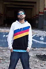 Image showing Fashion, outfit and man with sunglasses in a city, chill and attitude, young and stylish on urban background. Trendy, glasses and male person with confidence, casual and cool clothes while downtown