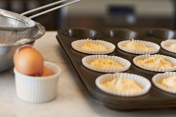 Image showing Cupcake tray, batter and baking in a kitchen with muffin mix or wrapper and cooking in a bakery. Closeup, paper cup and food with chef in a restaurant, coffee shop or cafe with sweet cake and pastry