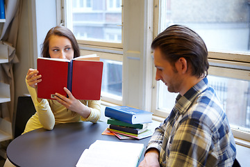 Image showing Education, college and couple studying in a library, learning and reading books together. Scholarship, focus and a man and woman sitting at a university table for research, knowledge and information