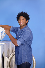 Image showing Laundry, portrait of a black man at washing machine and basket at laundromat with a smile. Hygiene, service and African male person cleaning clothes for health wellness or protection from bacteria