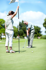 Image showing Woman with flag, old man or golfer on golf course for a birdie, putting stroke or exercise in retirement. Senior couple, mature or serious player training in golfing sports game driving with a club