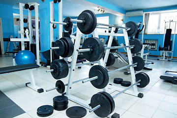 Image showing Barbell rack, gym interior and fitness with equipment for wellness, healthy bodybuilding or training. Exercise, workout or health club with metal weights on shelf, strong body development and sports