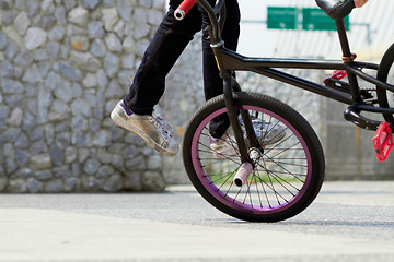 Image showing Legs, wheel and person on bicycle for trick, challenge and action at skatepark in city. Closeup, cycling stunt and urban biker in town with skill for balance, performance risk and freedom of motion