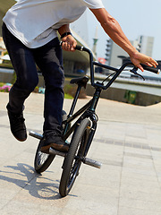 Image showing Bike, trick and closeup of man outdoor for sports, balance and action at urban skatepark. Male person, bicycle stunt and control on cycling wheels in city for skill, performance and freedom of motion