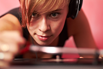 Image showing DJ, music and concert with a woman in headphones on a pink background to play an audio record. Party, festival and sound with a female performer playing a psychedelic vinyl at a dance or disco