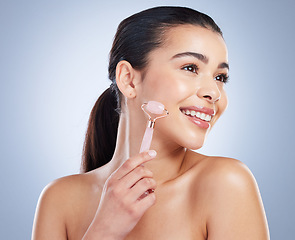 Image showing Derma roller, skincare and asian woman in studio for anti aging, cosmetic or face massage on grey background. Rose quartz, facial and lady wellness model with luxury, beauty or lymphatic drainage