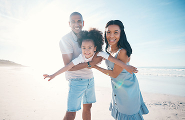 Image showing Beach, portrait and parents holding their child on the sand by the ocean on a family vacation. Happy, smile and girl kid flying and bonding with her young mother and father on tropical summer holiday