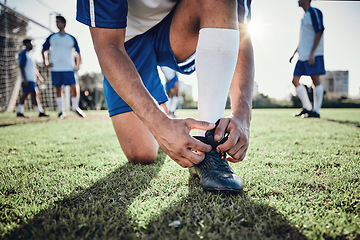 Image showing Hands, man and tie shoes on soccer field, prepare for training or fitness games. Closeup, football player or athlete getting ready with sneakers lace in sports, competition and contest on grass pitch