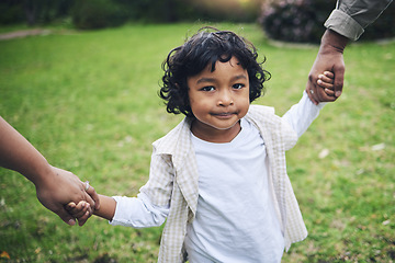 Image showing Nature, cute and boy child holding hands with his parents while walking in an outdoor park. Sweet, young and portrait of a kid with his mother and father in a green garden with love, care and support