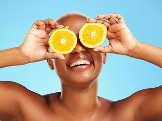 Image showing Orange, beauty and smile with a model black woman in studio on a blue background for a facial. Food, skincare and natural with a happy young female person holding a snack for health or wellness