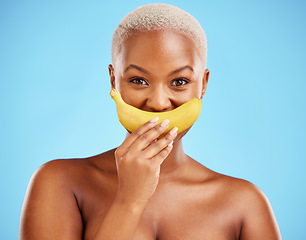 Image showing Black woman, banana and mouth for potassium, vitamin or fiber against a blue studio background. Portrait of happy African female person with organic fruit smile for health or wellness on mockup space