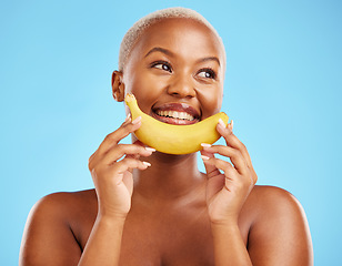 Image showing Beauty, smile and banana with a model black woman thinking on a blue background in studio. Skincare, idea and food with a happy young female person holding yellow fruit for natural wellness or detox