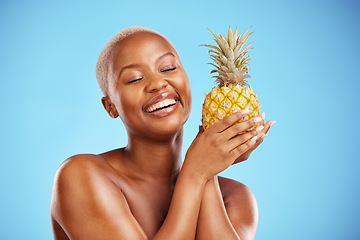 Image showing Happy black woman, pineapple and diet for natural nutrition or health against a blue studio background. African female person smile in happiness holding organic fruit for vitamin, fiber or wellness