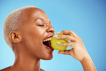 Image showing Black woman, apple and bite in diet, nutrition or health and wellness against a blue studio background. Face of African female person eating natural organic fruit for vitamin, fiber or food on mockup