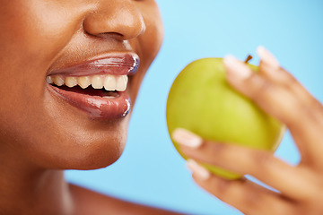 Image showing Black woman, mouth and apple in diet, nutrition or health and wellness against a blue studio background. Closeup of African female person eating natural organic fruit for vitamin, fiber or food snack