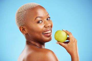 Image showing Happy black woman, portrait and apple for diet, nutrition or health and wellness against a blue studio background. Face of African female person with natural organic fruit for vitamin, fiber or food