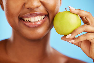 Image showing Woman, smile and apple for diet, nutrition or health and wellness against a blue studio background. Closeup of female person mouth with natural organic green fruit for vitamin, fiber or food snack