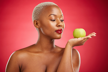 Image showing Black woman, apple and thinking for natural nutrition or healthy diet against a red studio background. African female person palm with natural organic green fruit for food snack, health and wellness