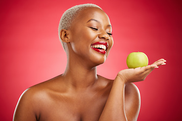 Image showing Happy black woman, apple and natural nutrition for diet, health and wellness against a red studio background. African female person smile and palm with organic green fruit for food, snack or meal