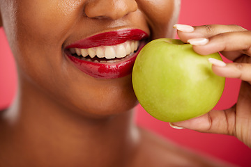 Image showing Woman, mouth and apple for natural nutrition, diet or health and wellness against a red studio background. Closeup of female person smile with lipstick and organic fruit for vitamin, fiber or food