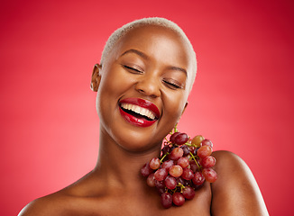 Image showing Beauty, smile and grapes with a model black woman in studio on a red background for health or nutrition. Skincare, happy and fruit with a young female person posing for wellness, diet or detox