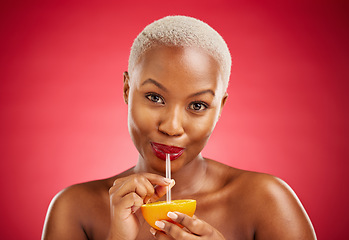 Image showing Black woman, portrait and drinking orange for vitamin C, diet or natural nutrition against a red studio background. African female person with organic citrus fruit, juice and straw on mockup space