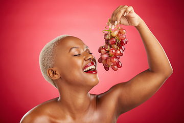 Image showing Happy, eating and black woman with grapes on a red background for nutrition, diet or health. Smile, beauty and an African model or girl with fruit, hungry and food for a detox isolated on a backdrop