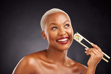 Image showing Thinking, face and woman with sushi and chopsticks in studio for healthy eating, beauty or food. Happy black female model with makeup idea on dark background for wellness, diet or seafood advertising