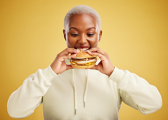 Image showing Burger, eating and woman or happy student on a studio, yellow background for restaurant promotion or deal. Hungry and excited african person or customer experience with fast food and hamburger bite